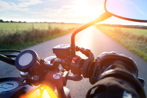 Blick über den Motorradlenker in Richtung Sonnenuntergang