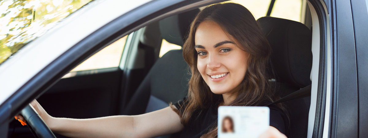 Junge Frau am Steuer mit Führerschein in der Hand